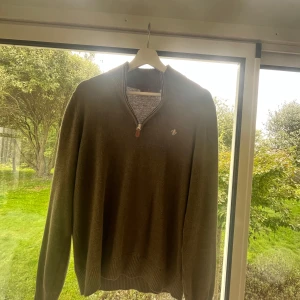 Grön morris stickad tröja med half zip - Mysig grön stickad tröja med ribbad krage och half zip-dragkedja. Liten broderad morris logga på bröstet och långa ärmar. Perfekt för lager-på-lager och chill höststil.