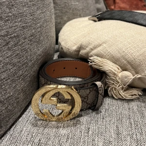 Beige bälte med GG-monogram - Ett beige bälte med GG-monogram och guldigt GG-monogram på framsidan som är väldigt stiligt och moget för dig som gillar orten eller grisch stilen, bältet kan också vara väldigt snyggt till kostymer och ger en unik stil som är snygg