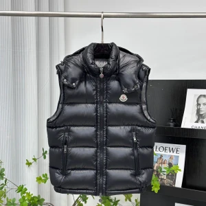 Svart dunväst från Moncler alla storlekar finns tillgängliga  - Snygg svart dunväst från Moncler med glansig finish, hög krage och avtagbar huva. Västen har två dragkedjefickor fram, quiltad design och klassisk Moncler-logga på bröstet. Perfekt för lager-på-lager och streetstyle.
