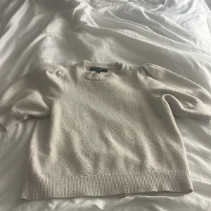 Beige stickad tröja från Vero Moda  - Superfin beige stickad tröja från Vero Moda med puffiga trekvartsärmar och rund halsringning. Tröjan har en mjuk och lite grovstickad känsla, perfekt för lager på lager. Passformen är normal och den har ribbade muddar vid ärmslut och nederkant. Den är i bra skick lite nopprig men inget som syns mycket annars är det inga fel.