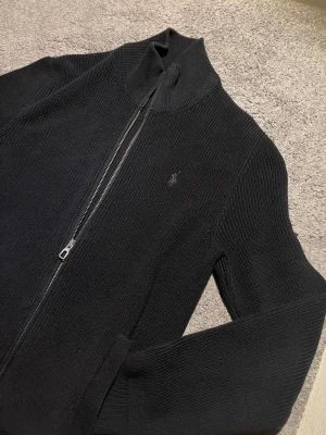Sweater Ralph Lauren Zip-Up 🧥 - Tidigare=999kr❌ Nu=889kr✅ This is a black Ralph Lauren zip-up sweater featuring the iconic logo. It appears to be in excellent condition with no visible wear.  ⭐️ Condition: 9/10 🎨 Color: Black 📦 Fast and careful shipping