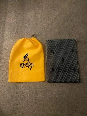 Datorfodral  - Snygg marinblå datorfodral  från … klassiskt rutigt mönster och dragkedja. Perfekt storlek för laptop eller dokument. Kommer med gul dustbag. Stilren design som sticker ut.