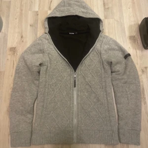 Grå fodrad stickad cardigan - Otroligt fet grå stickad fodrad cardigan med mönster. Passar perfekt nu till kallare väder.  Axel till midja är 63cm ungefär. Armhåla-armhåla är 44-45 cm ungefär. Priset kan såklart diskuteras!