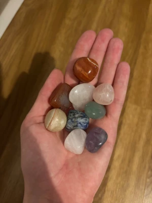 Stenar/kristaller - Säljer ett set med 9 polerade stenar/kristaller i olika färger och former,  Stenarna är i nyanser av röd, grön, blå, lila, ljusrosa och vit, och har både runda och fyrkantiga former. 