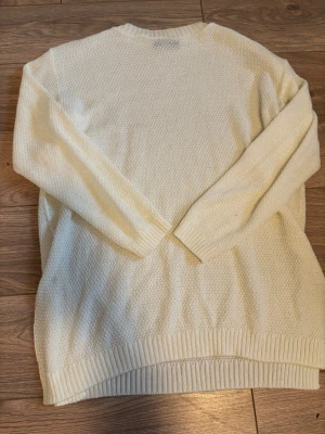 Vit stickad tröja från Boohoo - Säljer en vit stickad tröja från Boohoo med grovstickad struktur och ribbade muddar vid ärmslut och nederkant. Tröjan har långärmad design och rund hals, perfekt för att hålla dig varm och snygg under kyliga dagar.