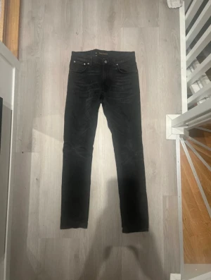 Svarta jeans från Nudie Jeans - Säljer ett par svarta jeans från Nudie Jeans i modellen Lean Dean. De har klassisk femficksdesign, svarta sömmar och Nudie-logga på bakfickan. W30 L32.