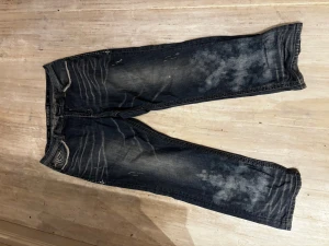 Affliction jeans med broderade fickor - Säljer ett par ljusblå Affliction Grant jeans med snygga broderade bakfickor och slitna detaljer. Jeansen har raka ben, kontrastsömmar och coola metalldetaljer. Materialet är klassisk jeans med tvättade effekter och mönstrade fickor som sticker ut‼️🔥buda gärna!