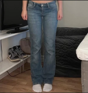 bootcut jeans låg midja - Säljer ett par klassiska supersnygga bootcut jeans i blå tvätt med låg midja och bootcut-ben. Jeansen har fem fickor, knapp och dragkedja framtill samt bälteshällor. Materialet är slitstarkt denim i bomull, perfekt för en chill och avslappnad stil.