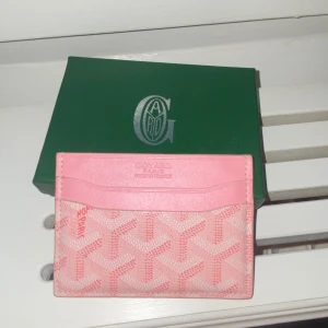 Goyarde korthållare - Supersöt plånbok från  i rosa med deras ikoniska mönster. Utsidan är ljusrosa med vita och rosa detaljer, insidan är knallgul. Perfekt för kort och cash, smidig att ha i fickan eller väskan. Lyxig och unik accessoar för dig som gillar färg och stil.