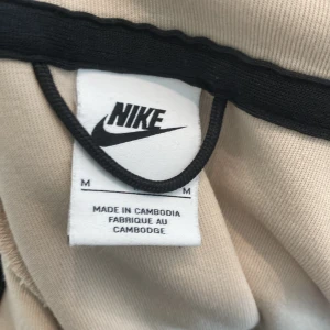 Nike teck beige och vit  - Tja det är en nike teck den är beige och vit storlek M.Den är ganska bra sick bara lite slit på dragtjedjan.annars väldigt bra allt funkar med den helt perfekt om man vill bara vara hemma och ha en chill dag.