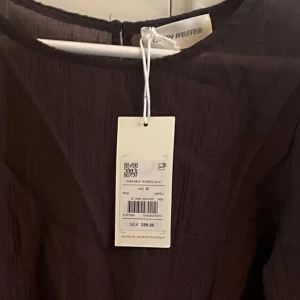 Ny brun top  från Carin Wester - Säljer en stilren brun  top från Carin Wester. Toppen har rund halsringning och är tillverkad i ett lätt, strukturerat tyg. Perfekt för dig som gillar minimalistisk och modern stil.