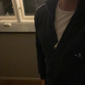 Blå half zip tröja från Gant - Säljer en marinblå långärmad tröja från Gant med half zip och ståkrage. Träjan har storlek XL men modellen på bilden är 180 cm och den passar nästan på honom vilket gör att jag skulle säga att den mer är L. 