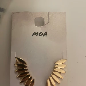 Guldiga örhängen från MOA - Snygga guldiga örhängen från MOA med ett coolt, bladliknande mönster. De är nickeltestade och har en modern, trendig design som verkligen sticker ut. Perfekta för dig som vill ha något extra till din look.