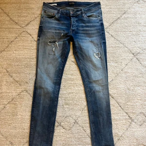 Blå jeans med slitningar från Jack & jonse  - Snygga blå skinny jeans från Jack & Jones med slitna detaljer och hål på låren | storlek: 31/32 | skick: 9/10 | modell: Slim fit Glenn| hör av dig vid frågor och funderingar!