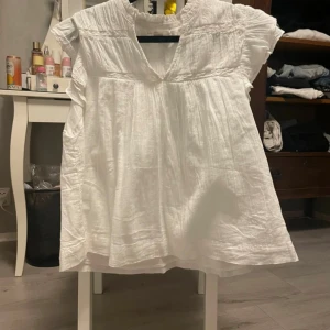 Vit blus med volangärm Gina Tricot - Supersöt vit blus från Gina Tricot med volangärmar och v-ringning. Luftig och lätt i bomull, perfekt för varma dagar. Blusen har en lös passform och fina rynkade detaljer upptill som ger en romantisk känsla. Storlek 170 men passar en xs