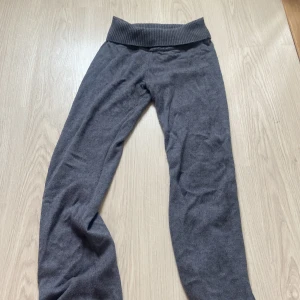Mörkgrå mjukisbyxor från Gina Tricot - Mysiga mörkgrå mjukisbyxor från Gina Tricot med bred ribbad midja. Perfekta för chill dagar hemma eller när du vill vara extra bekväm. Byxorna är i mjukt material och har en avslappnad passform.