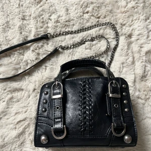 Svart handväska Zara med kedja och nitar - Cool svart handväska i skinn med silverfärgade nitar, spännen och kedjedetaljer. Från Zara 
