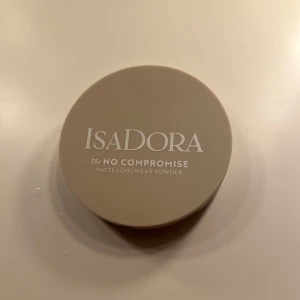 IsaDora No Compromise Matte Powder - Endast testad, Mattande kompaktpuder från IsaDora i färgen 60 Neutral Porcelain. Kommer i en beige rund dosa med spegel och pressat puder med IsaDora-logga. Vegansk, parfymfri och kliniskt testad formula för en naturligt matt finish.