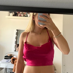 Rosa croppad topp med snörning - Säljer en rosa croppad topp med tunna band och öppen rygg med korsad snörning. Toppen har en lösare kant där uppe och knyts i ryggen för att justera passformen.🩷