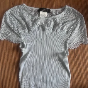 Ljusblå spetsblus från Rosemunde - Supersöt ljusblå blus från Rosemunde med ribbad kropp och fina spetsärmar. Toppen är väldigt strechig och nypris är 750kr