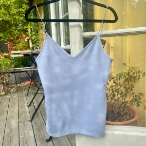 Ljusblå/ljuslila linnetopp med smala axelband - Säljer en ljusblå/ljuslila linnetopp med smala axelband och v-ringning. Enkel, stilren design utan mönster eller detaljer. Perfekt för varma dagar och enkel att matcha med olika outfits.