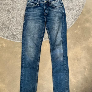 jeans Jack & Jones - Snygga blå jeans från Jack & Jones, modell Tapered/Mike. Jeansen har klassisk femficksdesign, normalhög midja och avsmalnande ben. Tillverkade i slitstarkt denim med snygga slitningar och detaljer. Perfekta för en avslappnad och trendig look.
