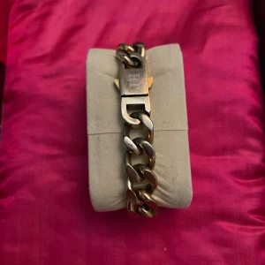 Chunky silverfärgat armband Johansson - Stilrent chunky armband i guldfärgad metall. Länkarna är breda och har en cool, robust känsla. Låset är rejält och har en graverad detalj. Perfekt för dig som gillar statement-smycken med klassisk vibe.