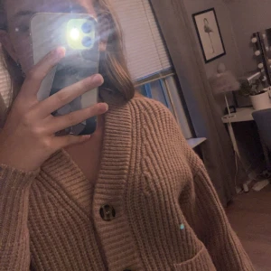 Rosa stickad tröja - Mysig rosa stickad kofta, den ser beige ut men är mer åt de rosa hållet irl. Den har 4 knappar i fint mönster, tröjan är väldigt mysig och helt perfekt till hösten. Säljer då den aldrig kommit till användning 