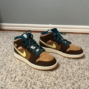 Nike Air Jordan 1 Mid brun/gul - Säljer mina Nike Jordan 1 skor som är i fel storlek och passar inte mig. De är använda en gång och orginalpriset är 1200kr. Storlek 40