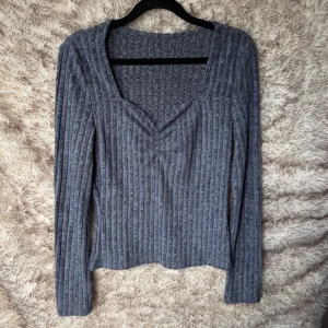 Blå  ribbad stickad tröja med v-ringning - Mysig blå stickad tröja med ribbat mönster och snygg v-ringning med rynkig effekt.  Långärmad och i mjukt material som känns skönt mot huden. 