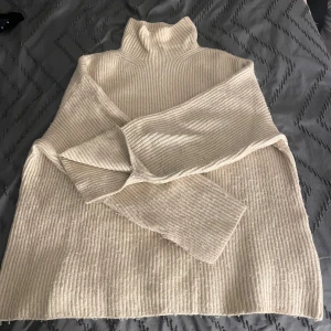 Beige ribbad polotröja - Säljer en beige ribbad polotröja med lång ärm och hög krage. Tröjan är stickad och har en loose passform, perfekt för lager-på-lager. Enkel och stilren design som funkar till allt. Supermjuk och skön att ha på sig under kyliga dagar.