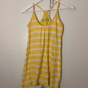 Gul och vit randig sommarklänning - Superfin gul och vit randig klänning från 365 Sunshine. Den är kort, har smala axelband och racerback-rygg. Ser lite gulare ut på bilden än i verkligheten! 