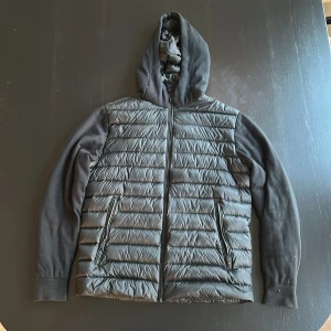 Svart cardigan Massimo Dutti - Svart fodrad cardigan från Massimo Dutti med huva och hel dragkedja. Jackan har quiltad framsida och rygg, två fickor med dragkedja. Hela cardiganen är fodrad så funkar perfekt under hösten och våran såväl som minus grader under vintern. Riktigt stilren och sparsamt använd nästan ny skick.