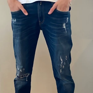 Replay jeans med slitningar, blå, 32/32 - Säljer ett par blå Replay jeans med coola slitningar och distressed detaljer på benen. Klassisk femficksmodell med slim fit och snygga kontrastsömmar. Perfekta för dig som gillar en avslappnad och trendig look.