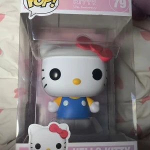 Funko Pop! Hello Kitty 50th Anniversary #79 - Stor Funko Pop! Hello Kitty 50th Anniversary #79, ca 31,5 cm hög. Figuren är i originalförpackning och ser ut att vara i nyskick utan synligt slitage. Perfekt för samlare och Hello Kitty-fans. Söt design med blå klänning och röd rosett.