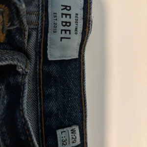 Blå jeans från Redefined Rebel W29 L32 - Säljer ett par klassiska blå jeans från Redefined Rebel. Jeansen har rak passform, normal midja och är tillverkade i slitstarkt denim. Snygga kontrastsömmar och två bakfickor. Perfekta för en chill och avslappnad stil.