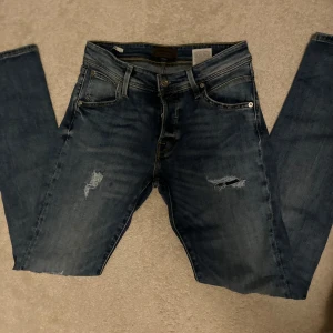 Jack & Jones jeans slim med slitningar - Tjena,säljer dessa riktigt feta Jack & Jones jeans strl W28/L32 i modellen slim/Glenn med otroligt feta slitningar perfekt nu när vi går mot somriga tider🌻jeansen är endast använd ca 5 ggr skick och har inga defekter. Fundera inte på att skriva.