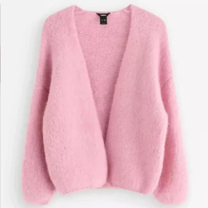 Ljusrosa kofta  - Supermysig ljusrosa kofta från Gina Tricot med oversized passform och långärmade, puffiga ärmar. Koftan är stickad och har en öppen front utan knappar eller dragkedja, vilket gör den enkel att slänga på över en topp. Perfekt för att ge din outfit en soft vibe.