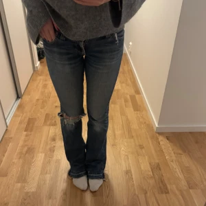 Lee jeans - Snygga blå jeans med bootcut passform och slitningar vid knäet och benslut. Jeansen har klassisk femficksdesign, låg midja och är tillverkade i jeansmaterial. Perfekta för en avslappnad och trendig look.