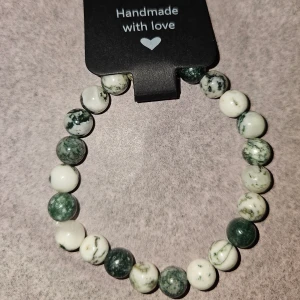 Handgjort pärlarmband agate  - Unikt handgjort armband med runda pärlor i grön och vit, agate. Pärlorna är trädade på elastisk tråd och har en cool, naturlig vibe. Perfekt för dig som gillar stilrena accessoarer med lite extra personlighet. Ca 17cm 