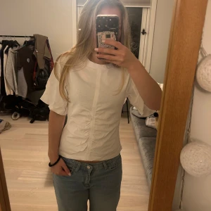 Vit figursydd t-shirt med rynk &other stories - Säljer en vit t-shirt med korta ärmar och snygg rynkdetalj framtill. Toppen är figursydd och har en enkel, stilren look med rund halsringning. 