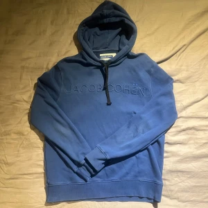 Blå hoodie från Jacob Cohën i bomull - Snygg blå hoodie från Jacob Cohën med broderad logga på bröstet. Tröjan har huva med snörning och är tillverkad i mjuk bomull. Perfekt för dig som gillar stilrena och bekväma plagg med premiumkänsla.