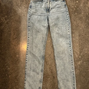 Vintage straight jeans från &Denim - Säljer ett par ljusblå vintage straight jeans från &Denim i storlek 34. De har hög midja och klassisk femficksdesign. Jeansen är raka i modellen och har en snygg tvättad look.