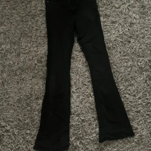 Svarta bootcut jeans med dragkedja - Svarta jeans med bootcut passform och klassisk femficksdesign. Byxorna har dragkedja i gylfen och är tillverkade i ett jeansmaterial. Snygga att styla med sneakers eller boots för en cool look.