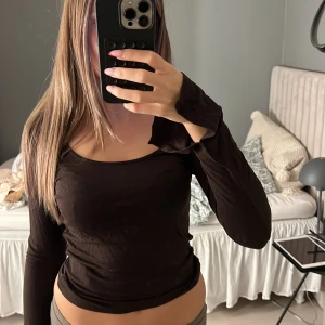 Brun långärmad topp med rund hals - Säljer en brun långärmad topp med rundad halsringning. Modellen är tight och sitter snyggt mot kroppen, perfekt att styla med jeans eller kjol. Tunn och mjuk i materialet för en skön känsla.