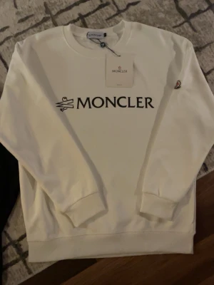 Vit hoodie - Säljer en helt ny Vit Moncler hoodie som är i storlek L. Håller dig stilig och varm, om du vill köpa den svarta så finns den i min profil, om det är något du undrar skriv direkt..Passa på och köp❄️