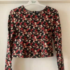 🍒Blommig croppad topp🍒 - 🍒FLIRTY FLORAL🍒Supersöt långärmad topp med blommigt mönster i rött, beige och grönt på svart botten. Croppad modell med rund hals och dragkedja i ryggen. Kommer i ett mjukt material med bomull och lite stretch.🍒