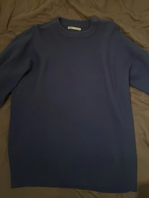 Mörkblå stickad tröja från Zara storlek M - Snygg mörkblå stickad tröja från Zara i storlek M. Tröjan har rund hals med ribbad kant och långa ärmar. Enkel och stilren design som funkar till många olika looks. Perfekt för dig som gillar klassiska plagg med modern touch.