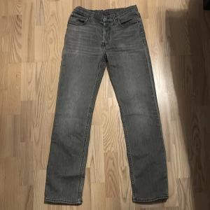 Levi's 501 grå jeans straight fit - Säljer ett par grå Levi's 501 jeans med klassisk straight fit och fem fickor. Jeansen har en mörkgrå tvätt, synliga sömmar och den ikoniska läderpatchen bak i midjan. Materialet är slitstark jeansbomull och passformen är normal med rak benlängd. Storlek 164. 