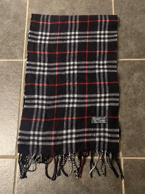 Burberry halsduk ”cashmere” - halsduk från Burberry | färg: blå röd vit | 100% cashmir | ny pris ca 4000kr | defekter: två hål, men syns ej när man använder den | skriv vid frågor | MD closet